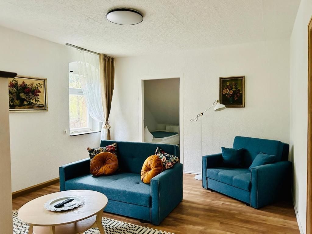 Un salon avec deux canapés bleus, une petite table ronde et un lampadaire.