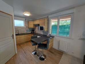 A modern kitchen with wooden cabinets, a black countertop, and a window overlooking a green area.