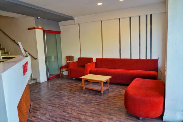 Una sala de estar moderna con un sofá rojo, una mesa de centro de madera y un reposapiés rojo.
