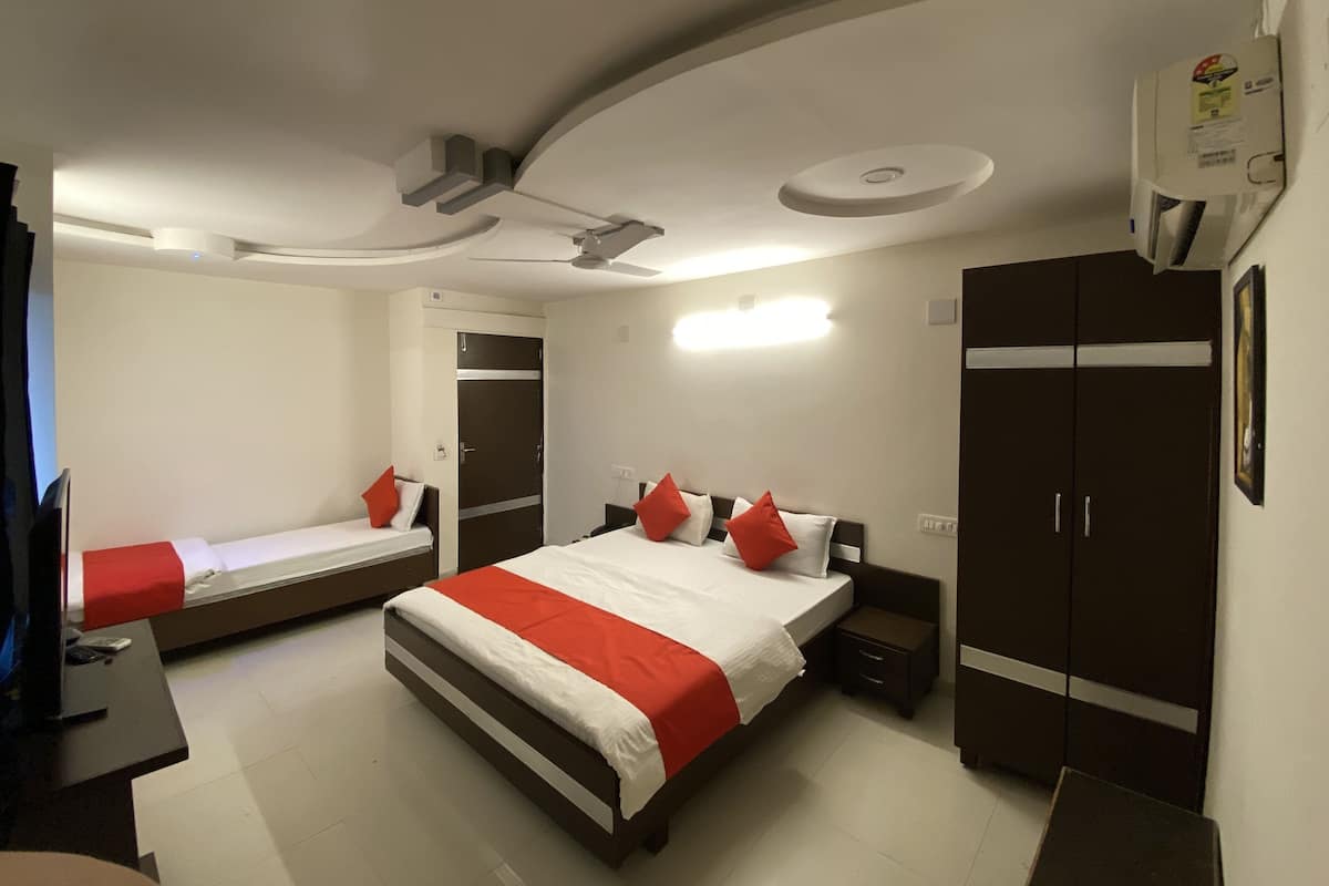 A hotel room with a large bed, a smaller bed, a wardrobe, a desk, and a ceiling fan.