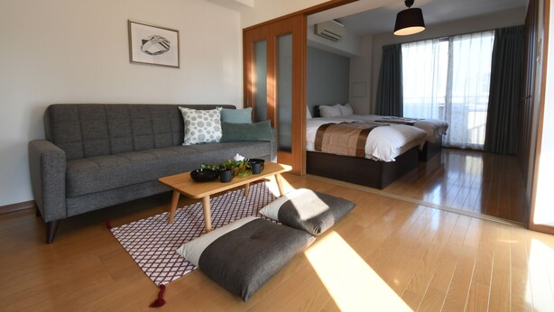 A modern living room with a grey sofa, a wooden coffee table, and a patterned rug. - Beau Belle Nagahori 902 (Osaka)