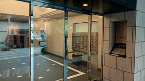 A hotel lobby with a glass entrance, a tiled floor, and a visible elevator. - Beau Belle Nagahori 902 (Osaka)