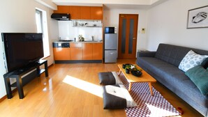 A compact living space with a kitchen, a sofa, a TV, and a dining area. - Beau Belle Nagahori 902 (Osaka)