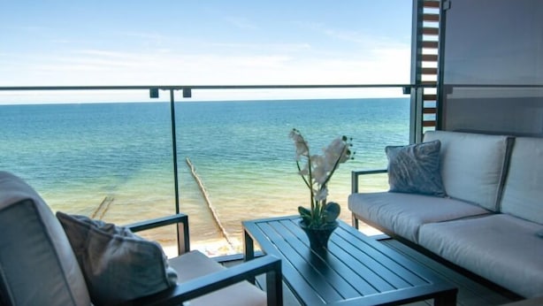 A balcony with a view of the sea, a sofa, a table, and a vase with flowers. - Apartament Sailor z widokiem na morze - Nadmorski Luksus (Ustronie Morskie)