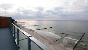 A beach with a wooden deck and a glass railing overlooking the water. - Apartament Sailor z widokiem na morze - Nadmorski Luksus (Ustronie Morskie)