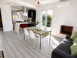 A modern kitchen with a dining area, a sofa, and a TV.