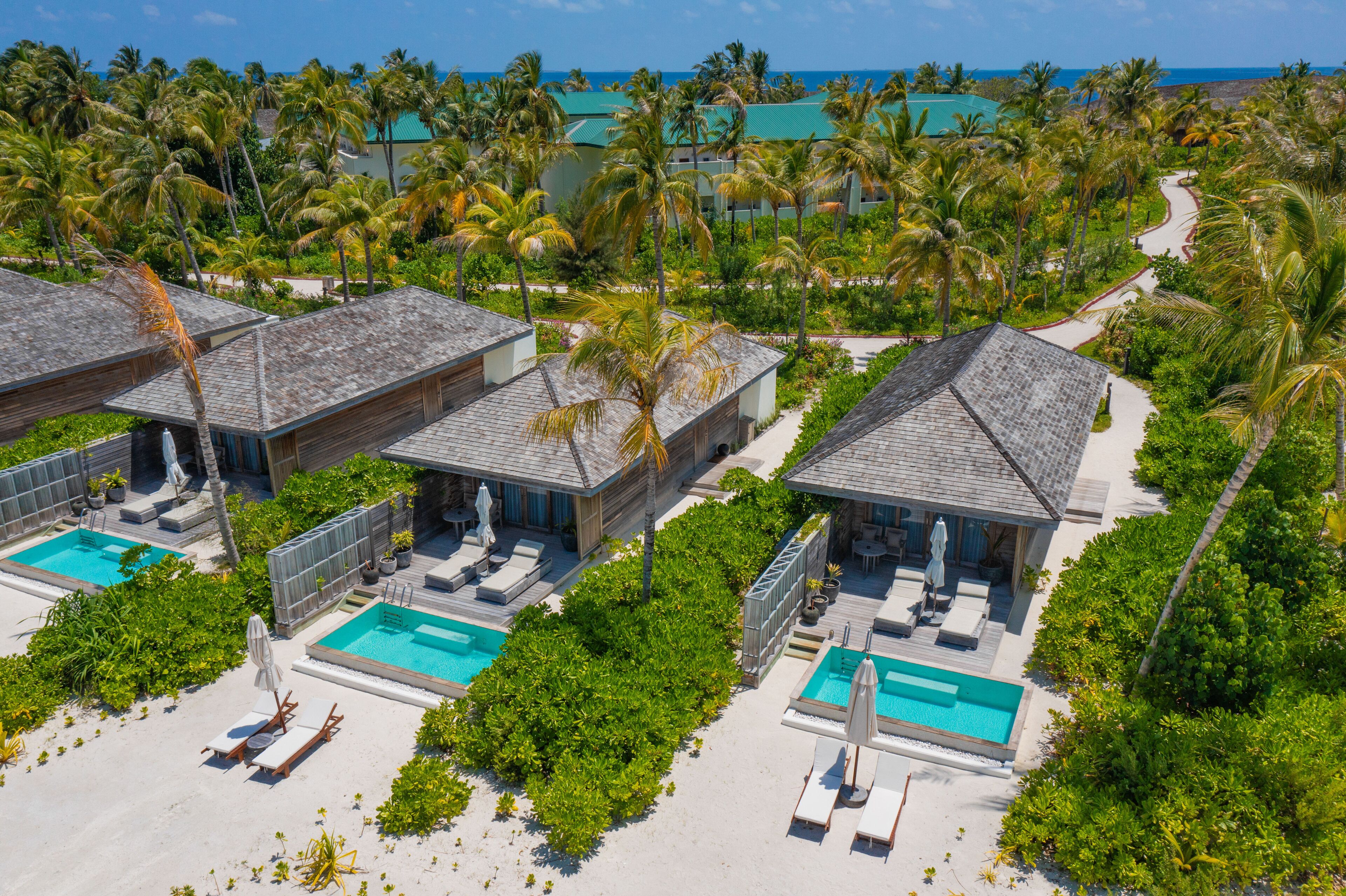 A resort with multiple bungalow-style accommodations, each with a private pool and direct access to a sandy beach.