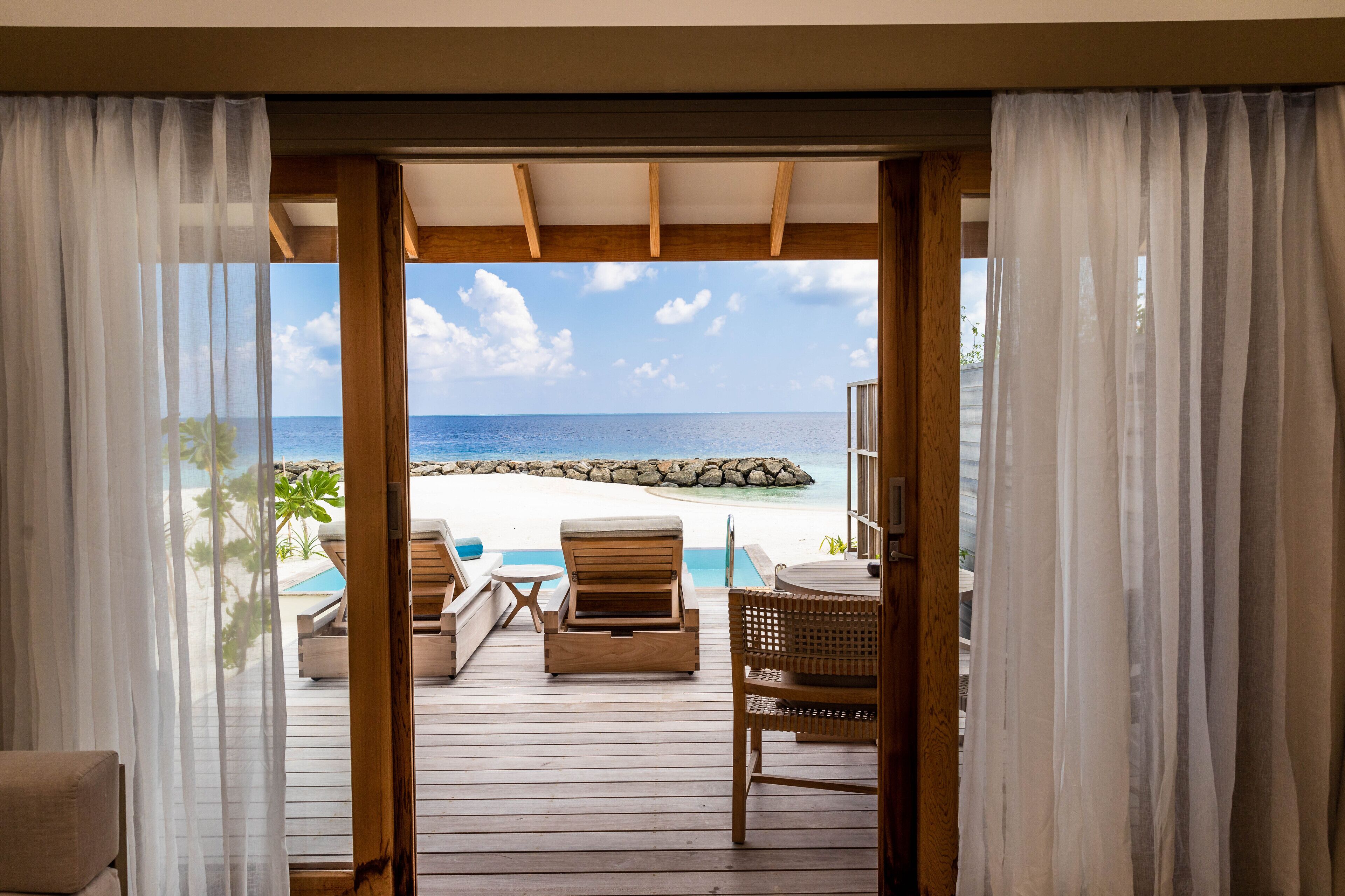 Una terraza de madera con vista a una playa y al océano.