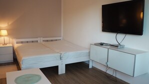 Et hotelværelse med seng, sengebord, lampe, fjernsyn og et lille skab.