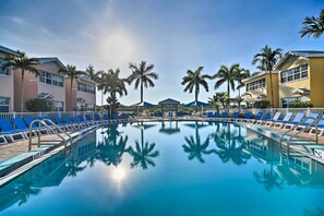 A swimming pool with blue lounge chairs, palm trees, and a clear sky. - Resort Condo w/ Beach Access in Indian Shores! (Indian Shores)