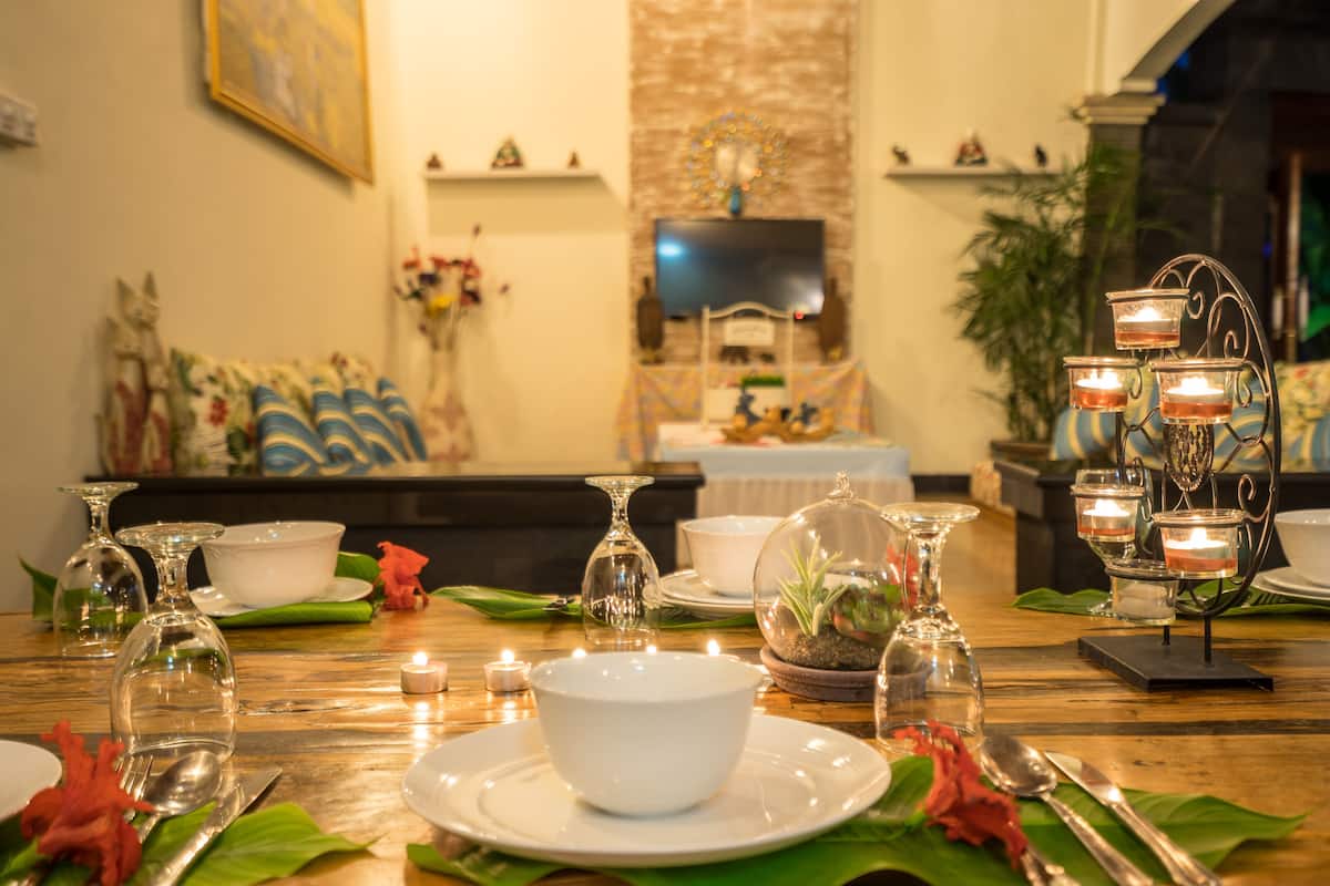 A dining table set with white plates, silverware, and clear glassware.