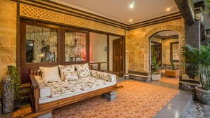A spacious lobby with a wooden sofa, patterned cushions, and a tiled floor. - Villa Mia And Spa (Seminyak)