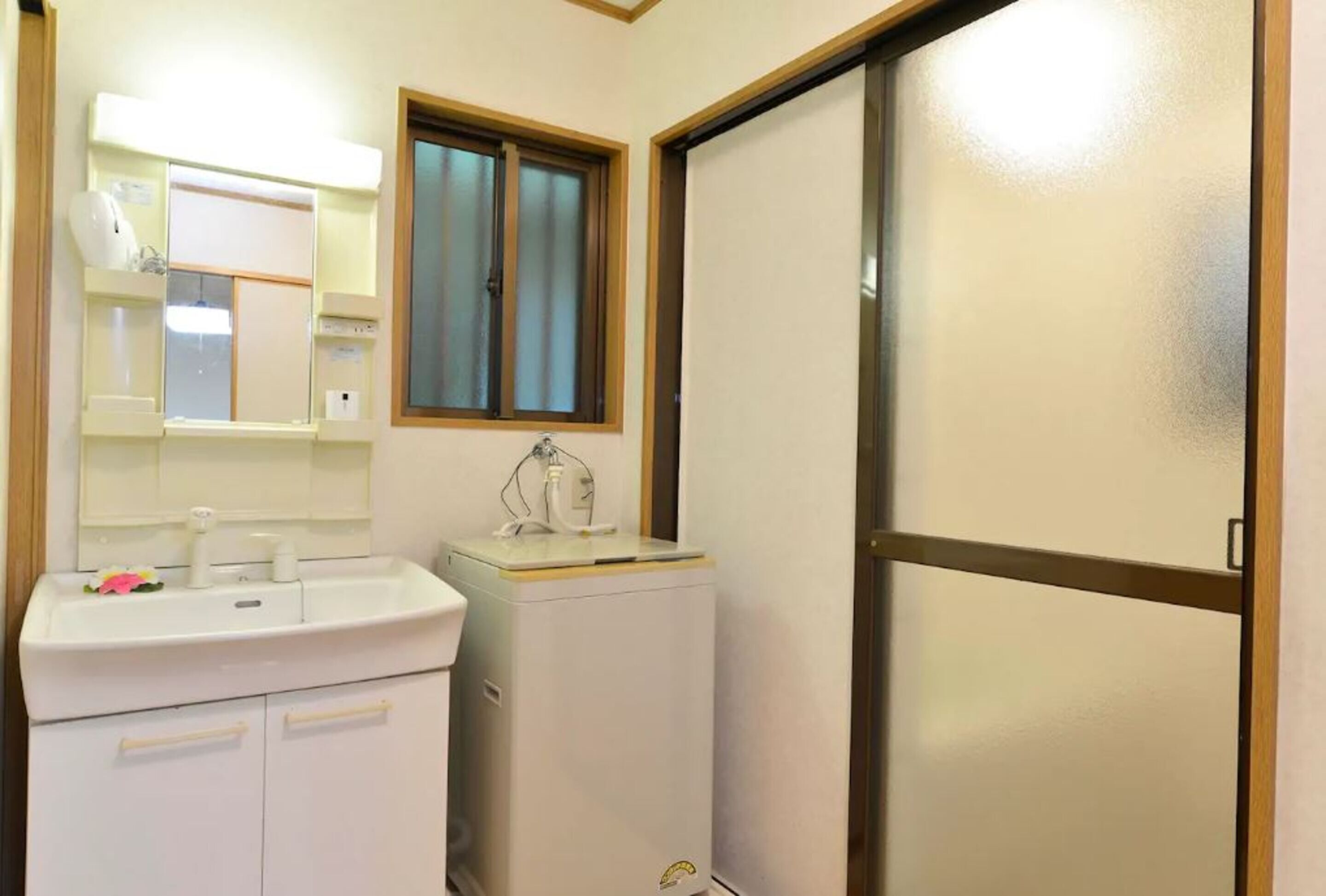 A bathroom with a sink, mirror, window, and a sliding door.
