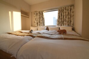 Een hotelkamer met een groot bed, een raam met bloemen gordijnen en uitzicht op de stad.