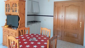 A compact kitchen with a stove, cabinets, and a dining table with chairs. - Colera Apartment B in Costa brava (Colera)