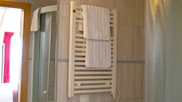 A bathroom with a sink, mirror, towel rack, and a shower area.