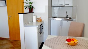 Une cuisine de taille réduite avec des meubles blancs, un évier en acier inoxydable et une porte en bois.