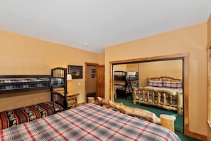 A room with bunk beds, a wooden log bed, and a large mirror reflecting the room.