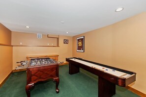 A room with a foosball table, pool table, and a billiards table.