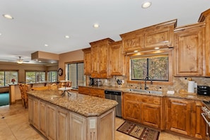 A kitchen with wooden cabinets, granite countertops, and a central island.