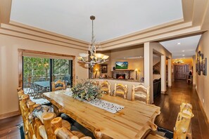 A spacious dining area with a wooden table and chairs, a chandelier, and a fireplace.
