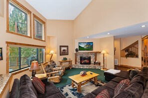 A spacious living room with a fireplace, comfortable seating, and large windows.