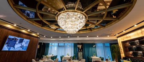 Un espace de restauration luxueux, agrémenté d’un grand lustre, de tables rondes et de sièges confortables.