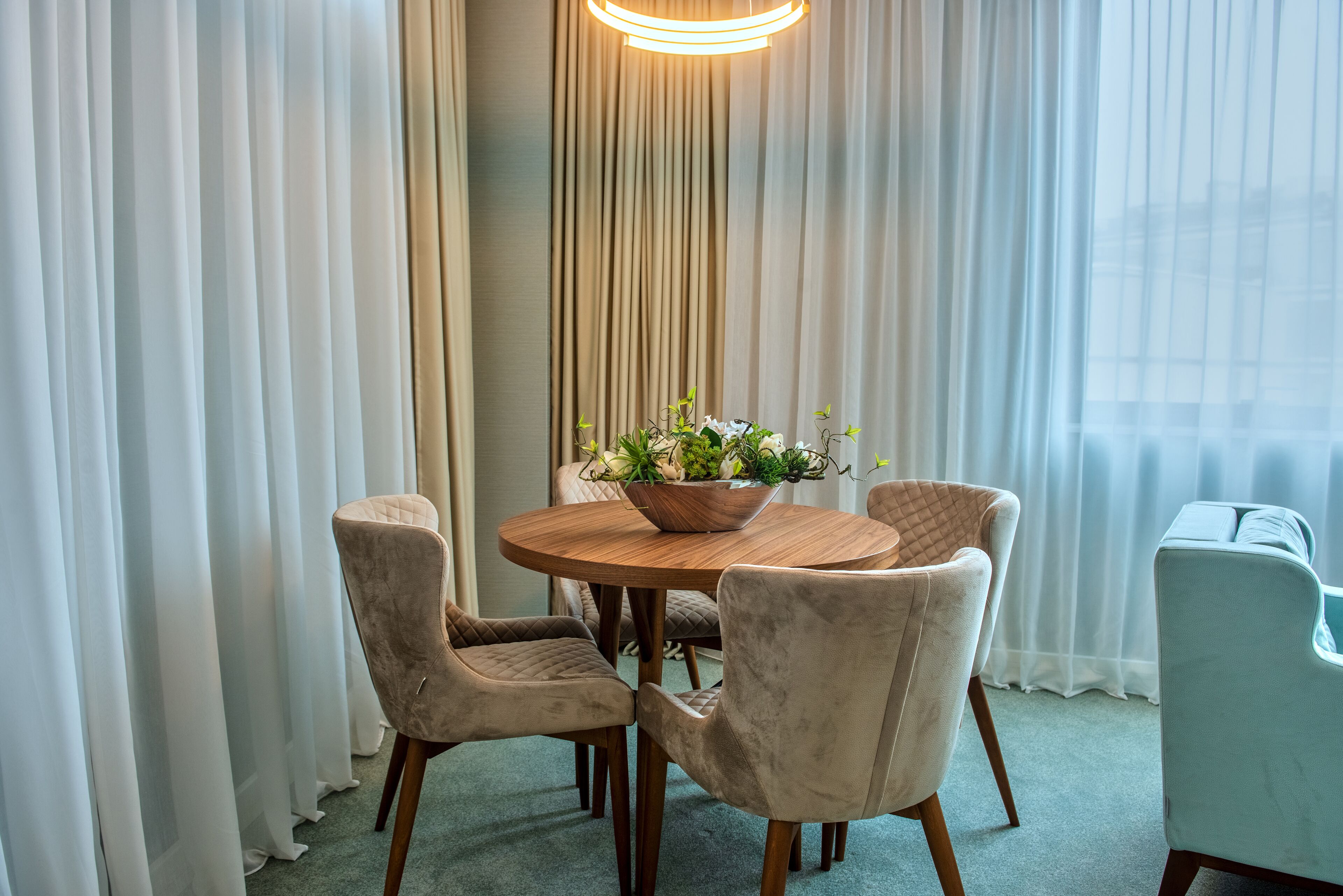 A dining area with a round wooden table, four cushioned chairs, and a floral centerpiece.