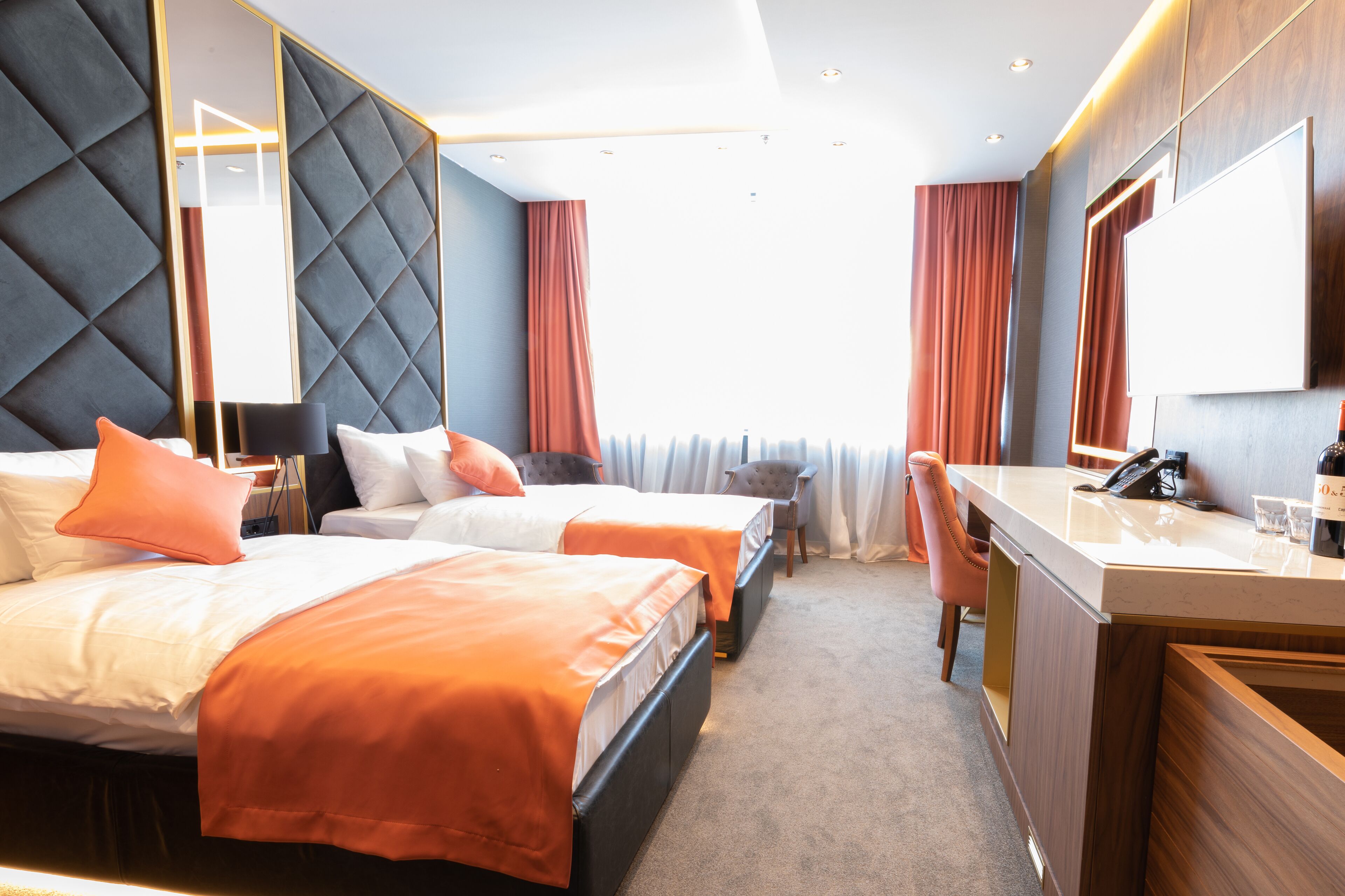 Ein Hotelzimmer mit zwei Betten, einem Schreibtisch und einem Spiegel.