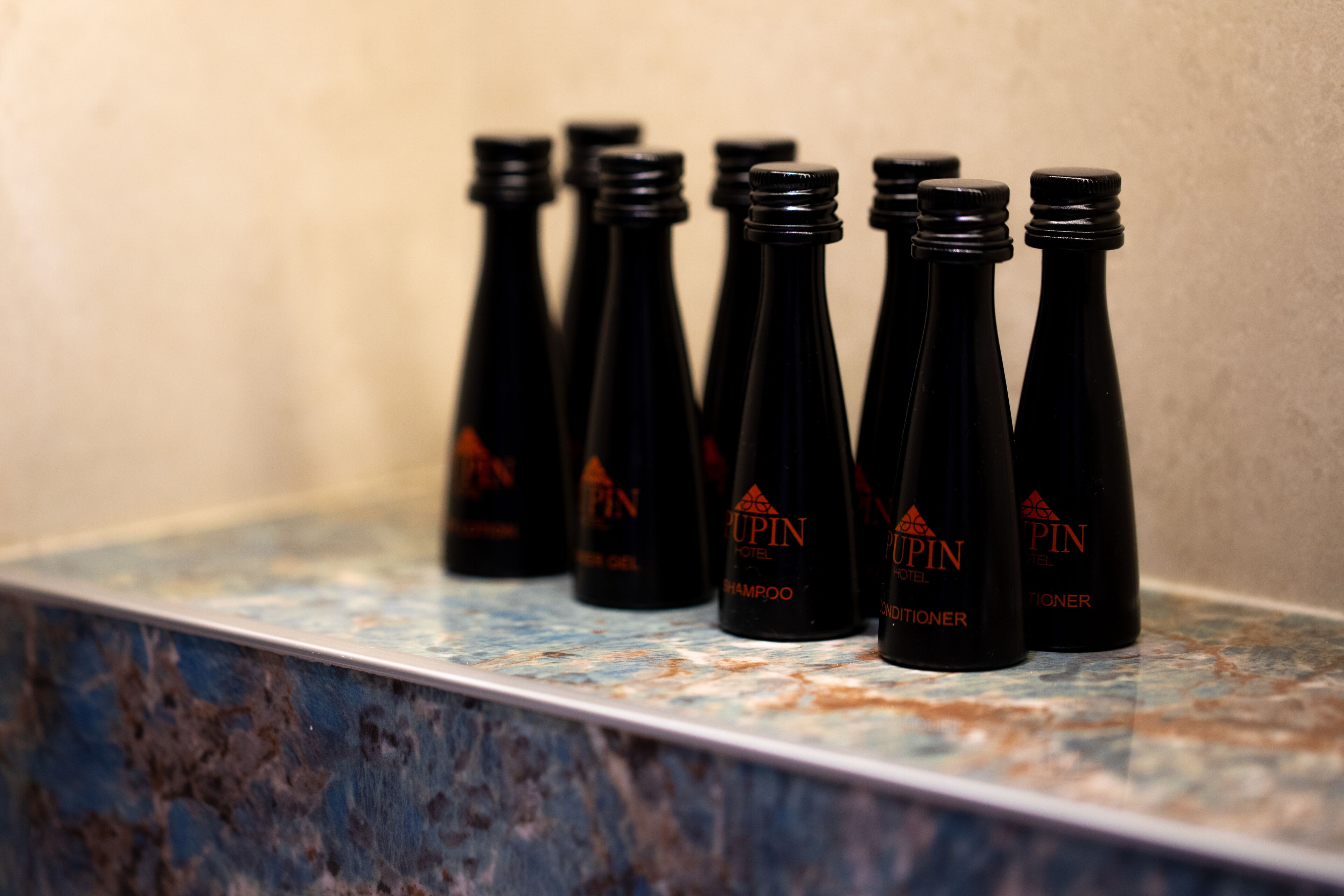 A row of black bottles with labels on a marble countertop.