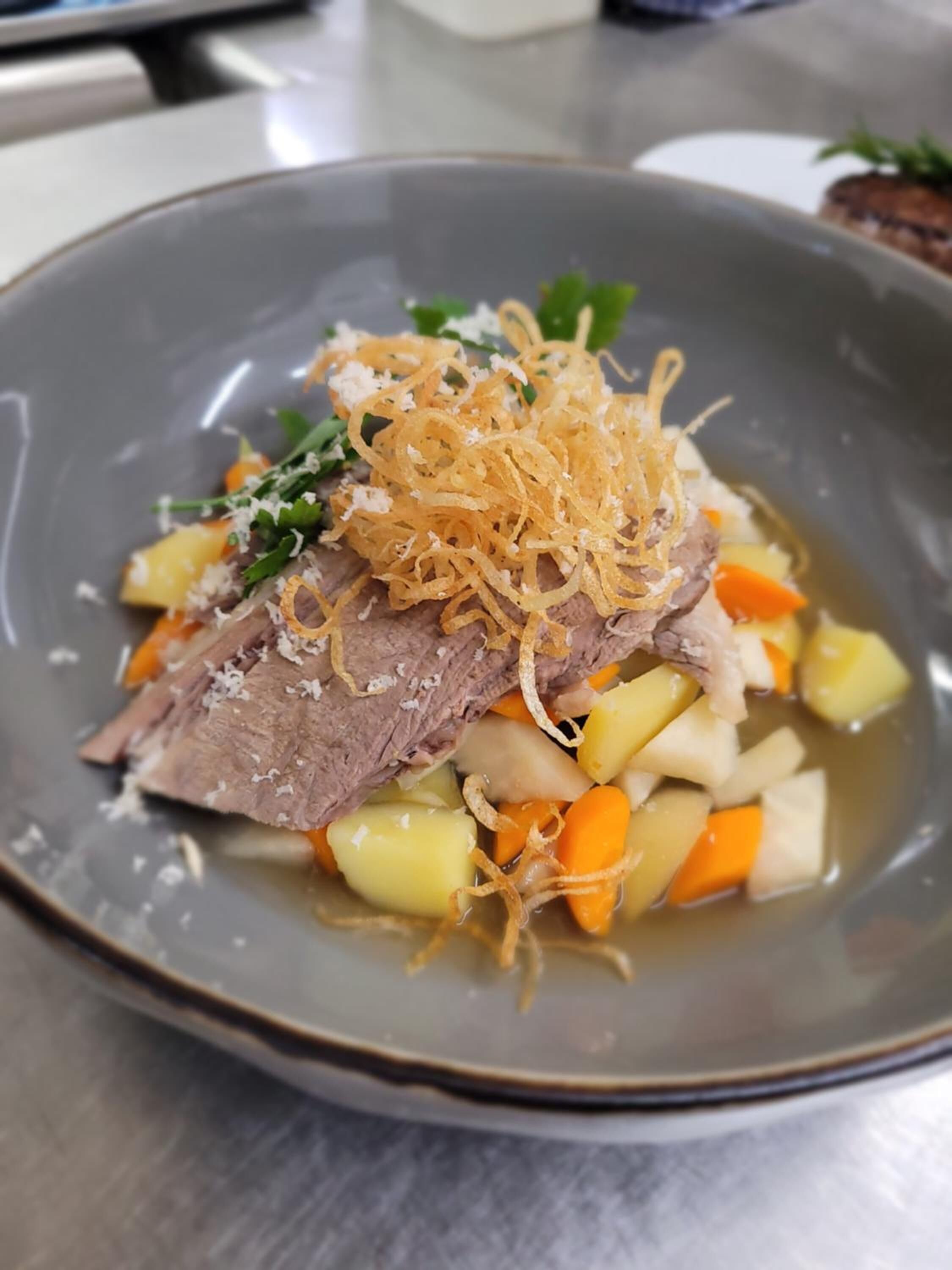 Prato de comida com carne, batatas, cenouras e acompanhamentos.