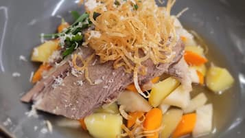 Prato de comida com carne, batatas, cenouras e acompanhamentos.