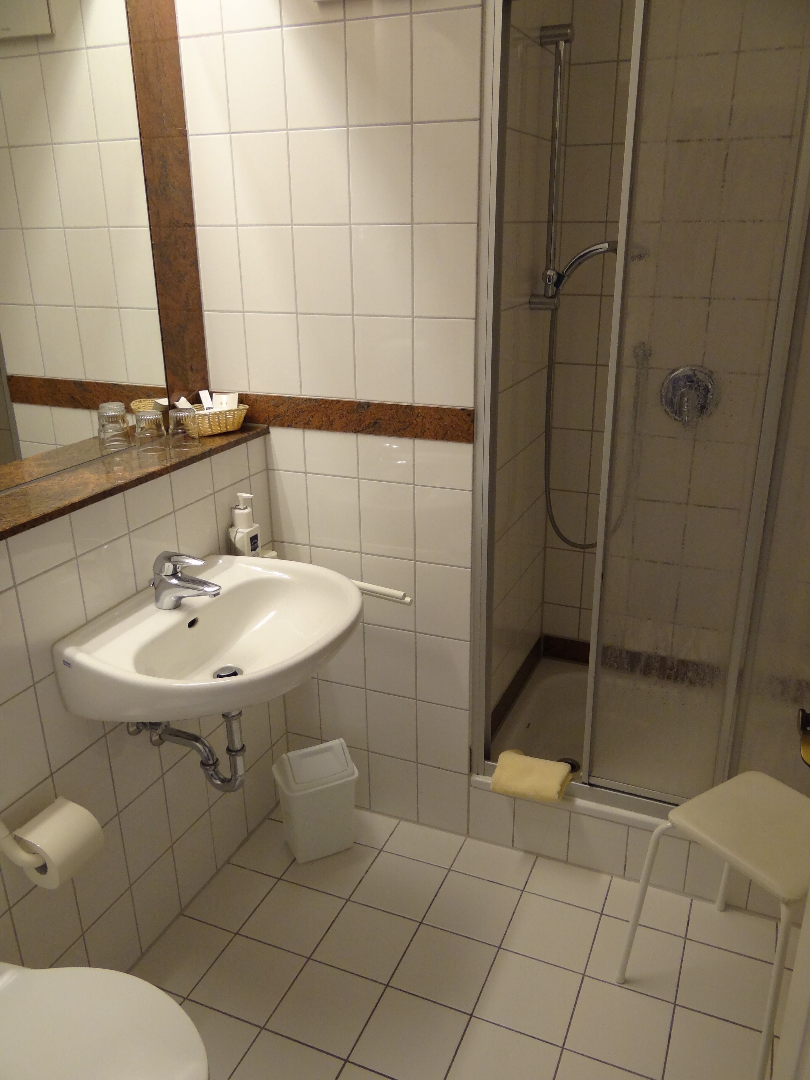 A bathroom with a sink, mirror, and shower.