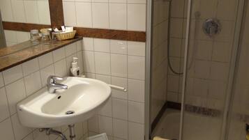 A bathroom with a sink, mirror, and shower.