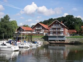 A lakeside property with a large house featuring balconies and a dock with boats.