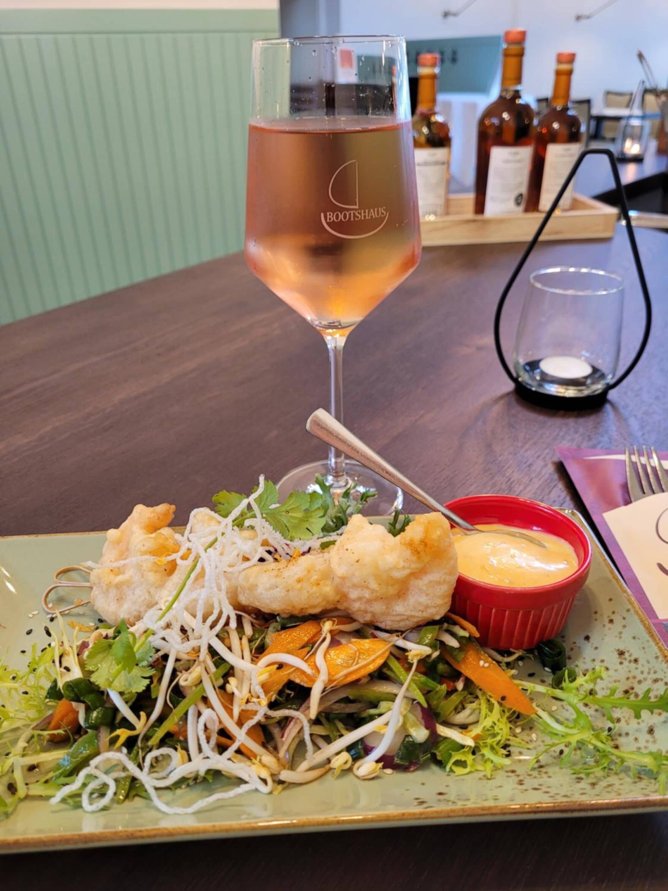 A dining table with a plate of food, a glass of wine, and a candle.