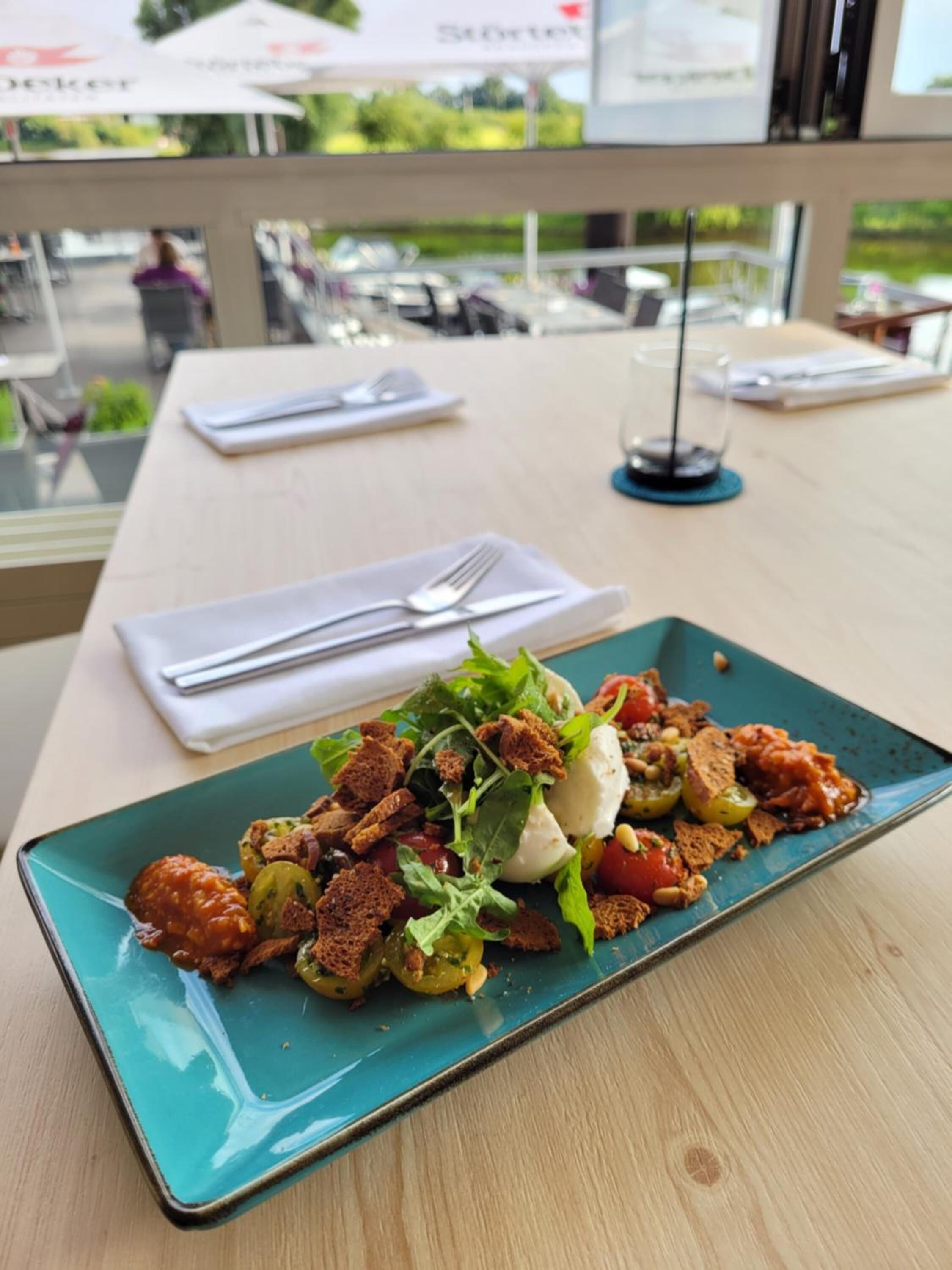 A table with a plate of food, a fork, and a napkin.
