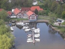 A marina with several boats docked, a pier, and a building with a red roof.