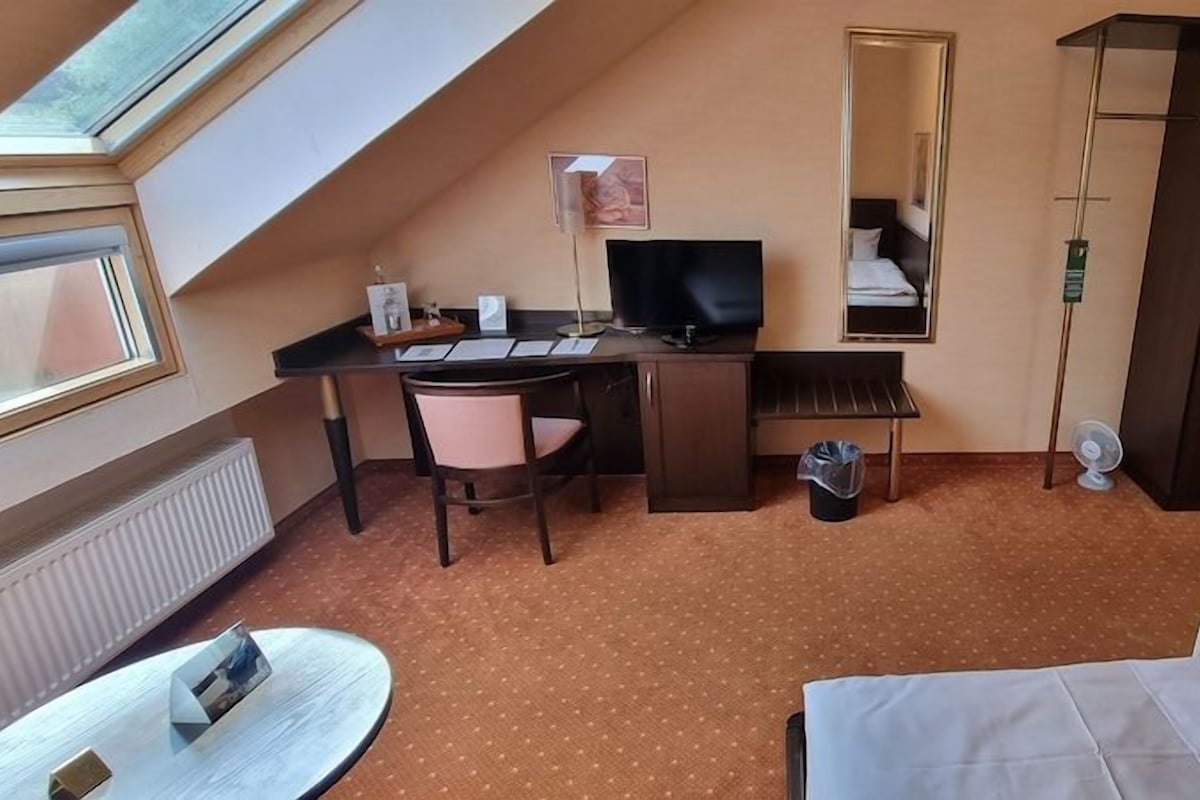 Habitación de hotel con escritorio, silla, cama y una ventana grande.