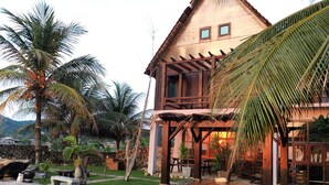 A wooden house with a pool, surrounded by palm trees and a stone wall. - Kijalena Beach BnB (Kijal)