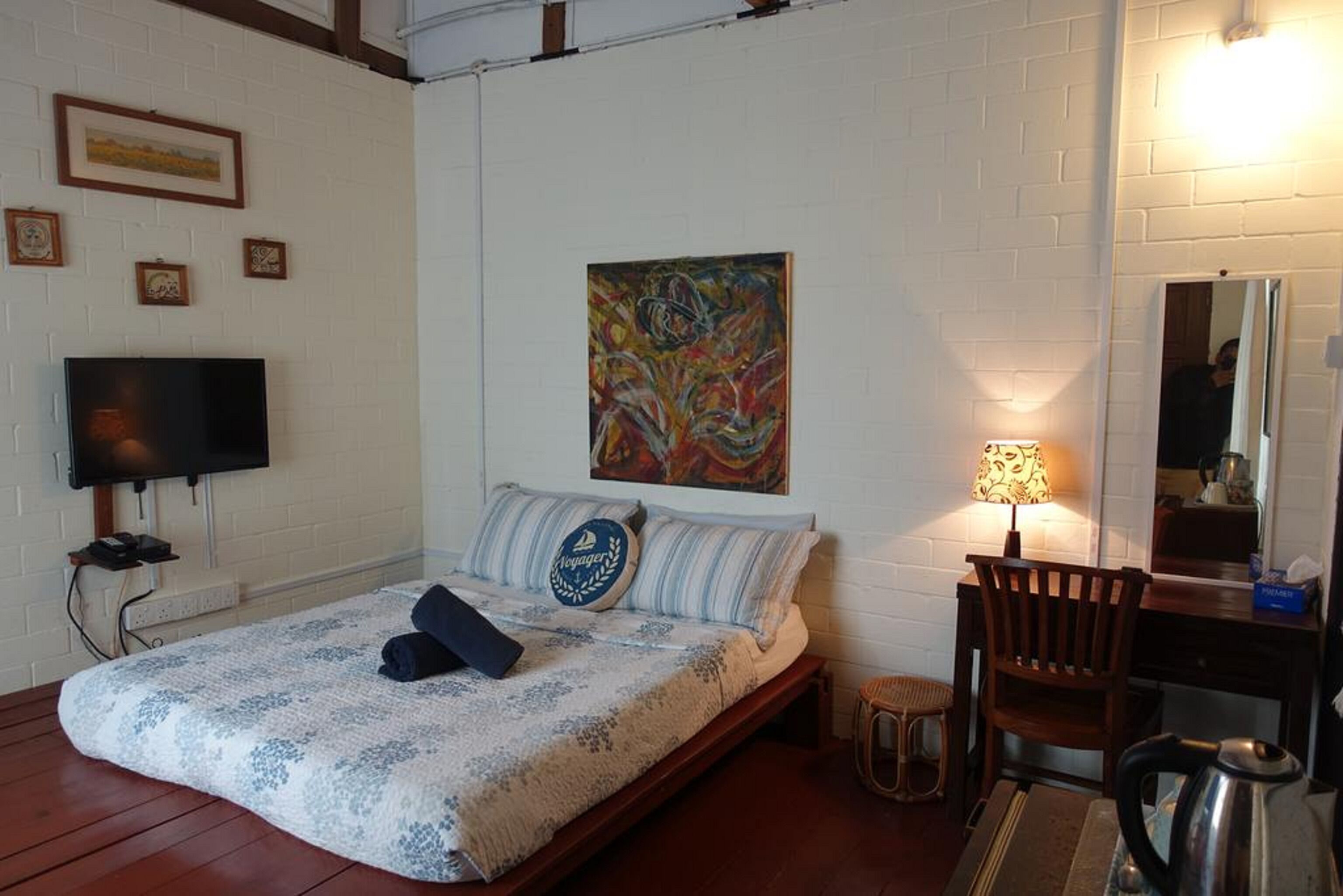 Une chambre à coucher avec un lit, une télévision, un tableau, une lampe et une chaise.