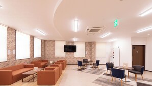 A spacious lobby with a seating area, a flat-screen TV mounted on the wall, and a reception desk. - Hotel Frente Hirono (Hirono)