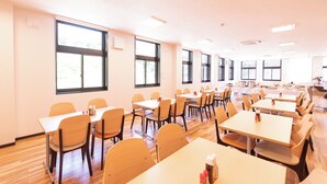 A spacious room with multiple tables and chairs, large windows, and an air conditioning unit on the ceiling. - Hotel Frente Hirono (Hirono)