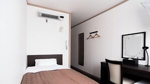 A hotel room with a bed, a desk, a chair, a mirror, and an air conditioning unit. - Hotel Frente Hirono (Hirono)
