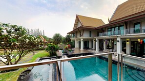 A modern house with a large swimming pool, a covered patio, and lush greenery. - Grace Villa Pattaya By DDM Siam (Bang Lamung)