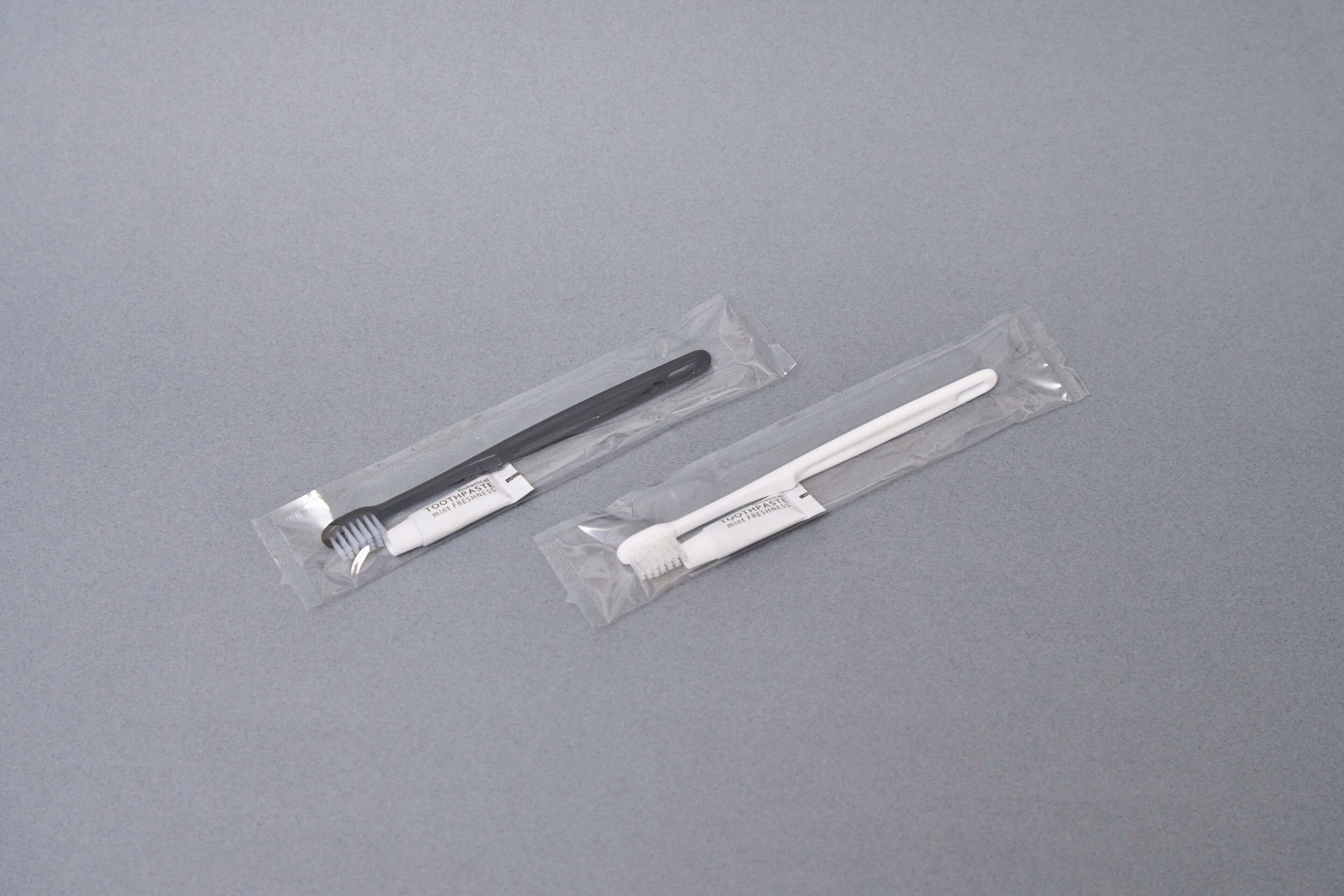 Dos cepillos de dientes en envases de plástico transparente sobre una superficie gris.