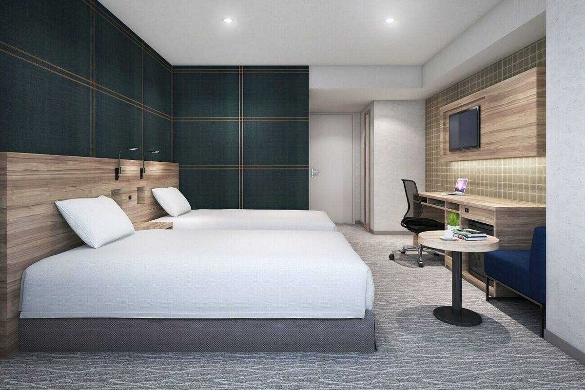 Una habitación de hotel moderna con dos camas, un escritorio, una silla y un televisor montado en la pared.