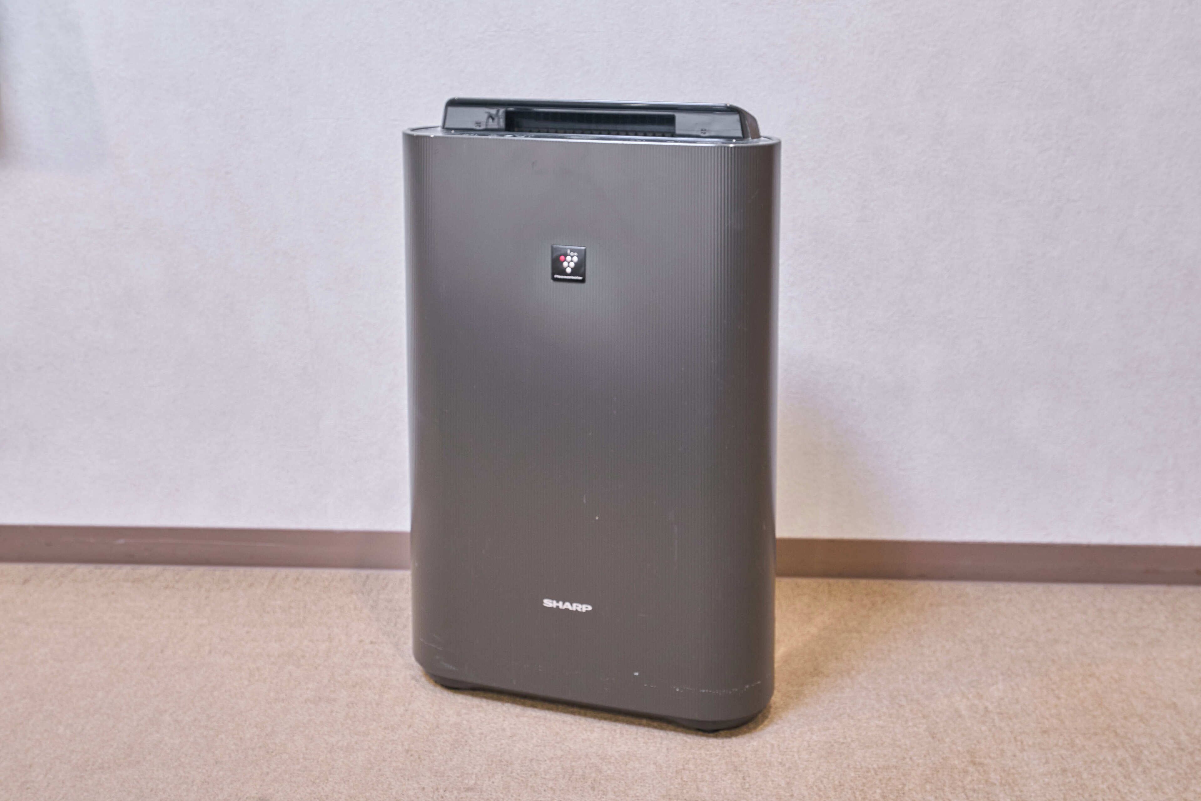 A gray, stationary device with a control panel and a brand name 'SHARP' on the bottom.