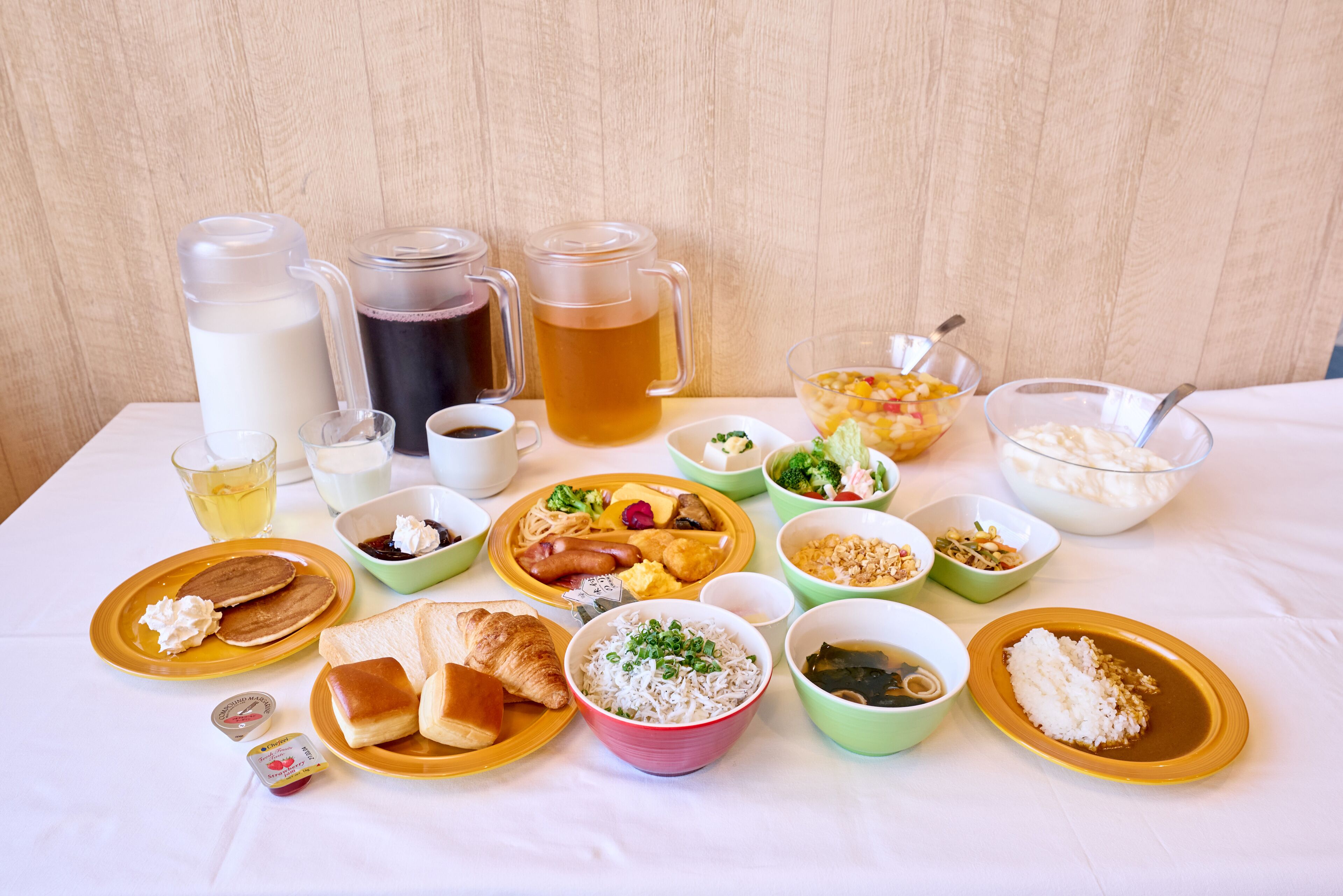 Une table dressée avec divers aliments et boissons, notamment des assiettes, des bols et des tasses.