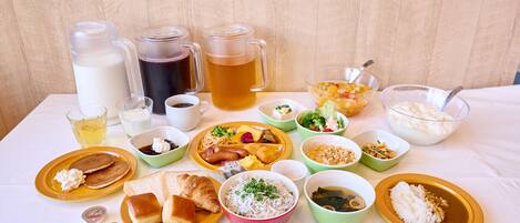 Une table dressée avec divers aliments et boissons, notamment des assiettes, des bols et des tasses.